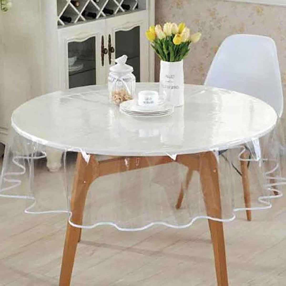 Nappe ronde transparente en PVC posée sur une table en bois naturel dans un intérieur lumineux.