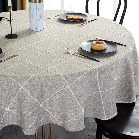 Nappe ronde en coton et lin avec quadrillage brodé, posée sur une petite table en bois.