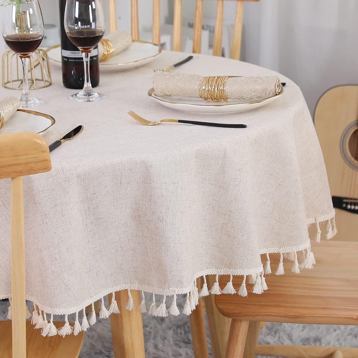 Nappe ronde beige à franges posée sur une table en bois dans une salle à manger lumineuse