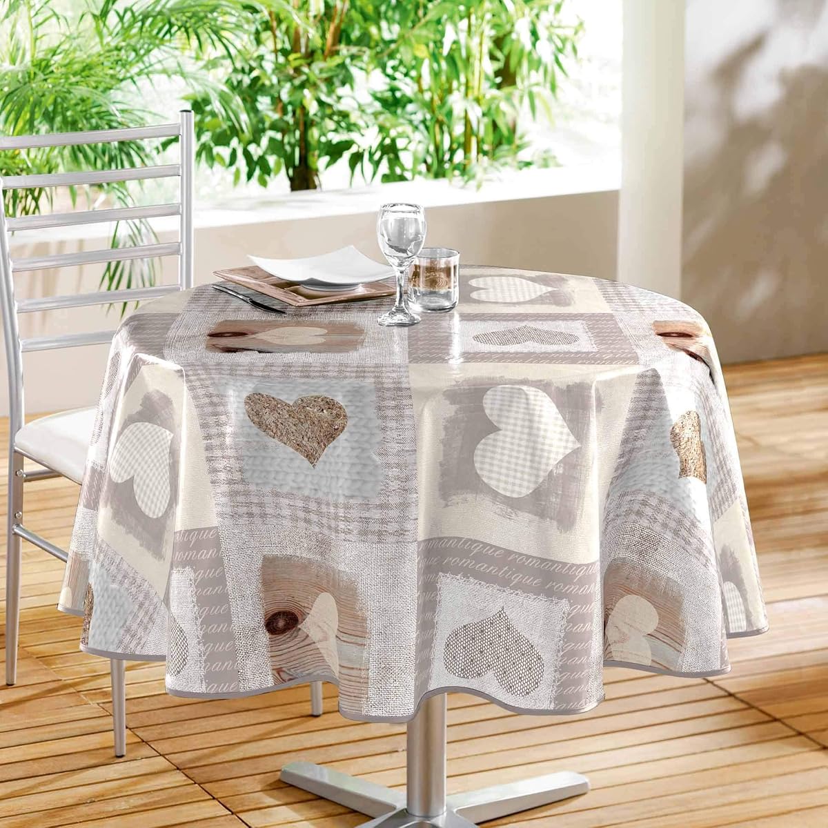 Nappe ronde en PVC imprimé à motif géométrique, dépliée sur une table de repas dans un intérieur lumineux.