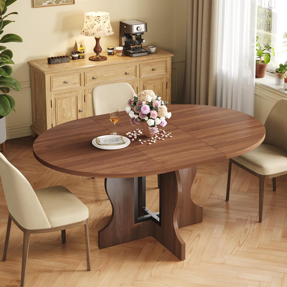 Table Mondeer extensible en finition noyer, déployée en ovale avec son piètement croisé en X.