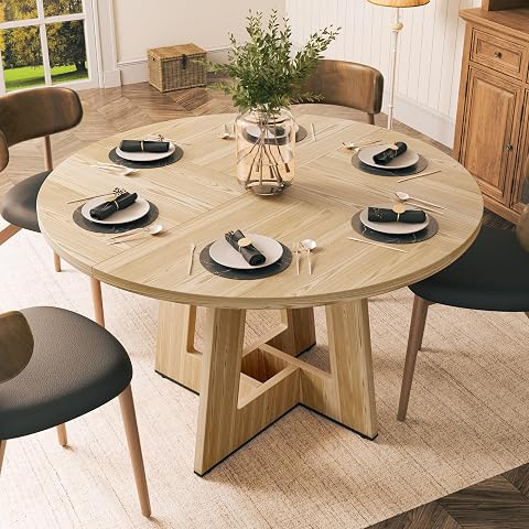 Table ronde en bois naturel avec plateau épais et piètement croisé dans une salle à manger lumineuse