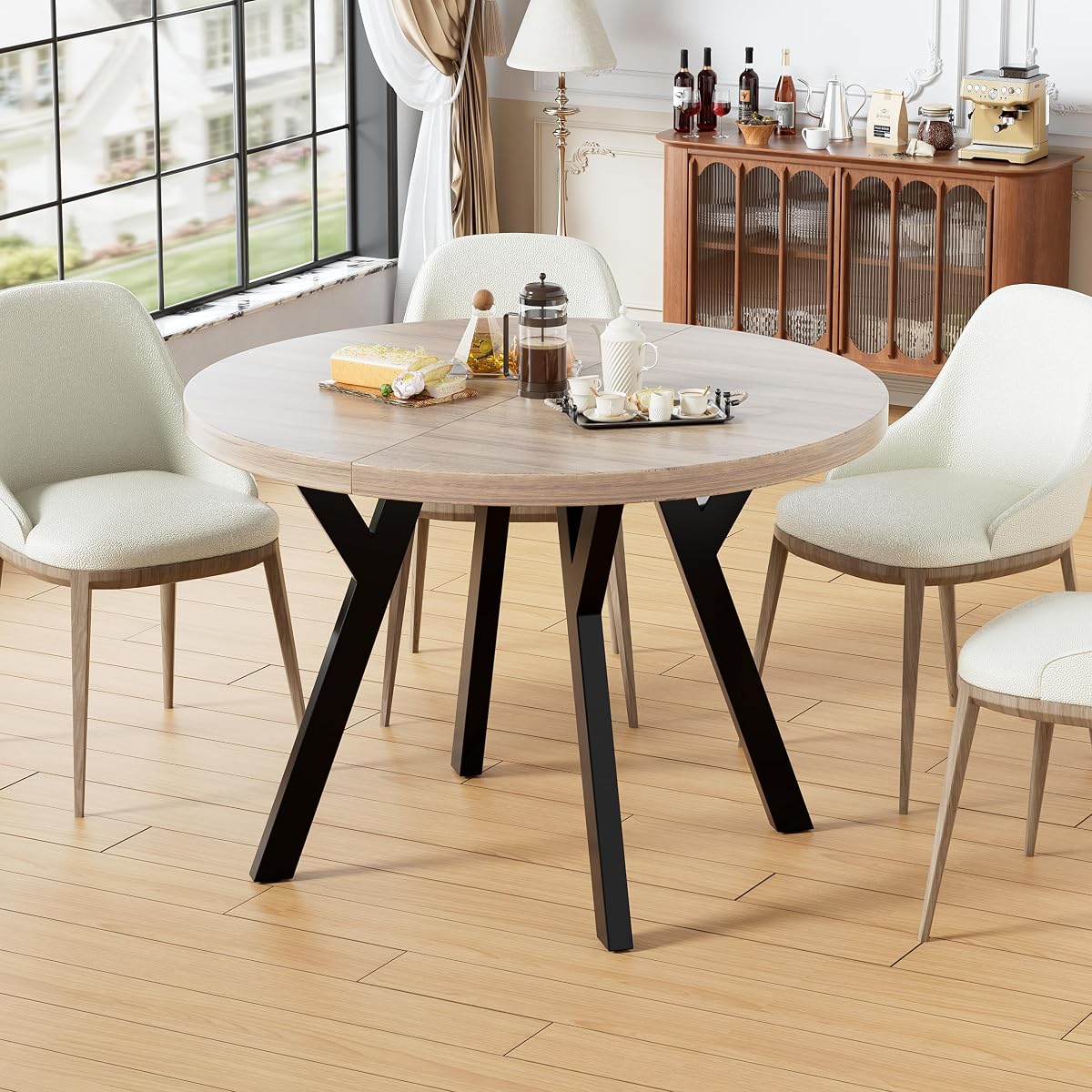 Table à manger ronde blanche extensible en ovale, avec piètement araignée noir dans une salle à manger lumineuse