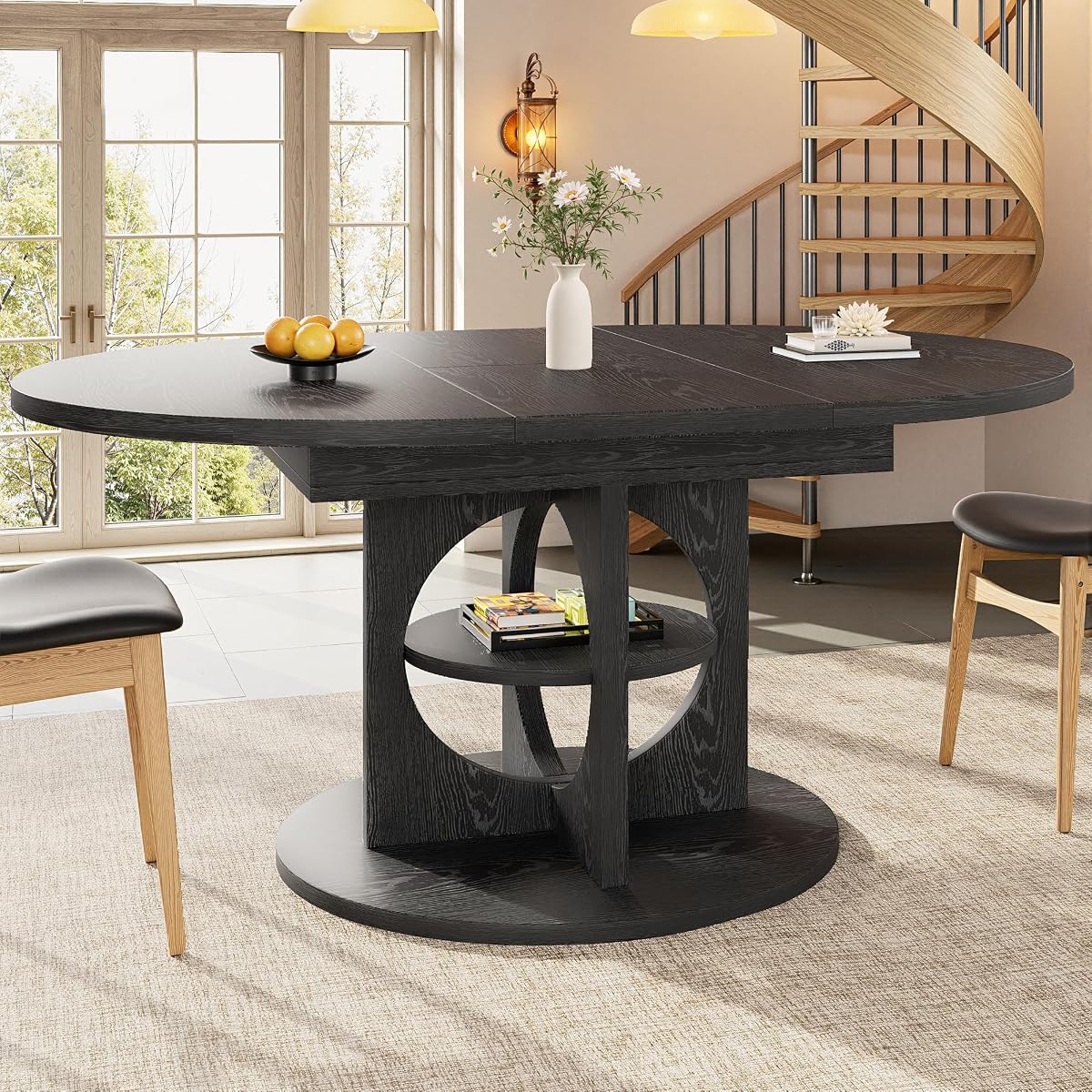 Table à manger noire extensible en format ovale, avec étagère traversante dans le pied central.